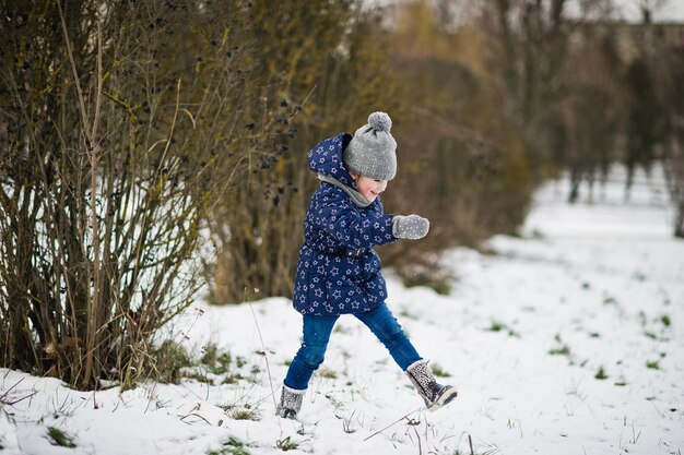 Niña linda divirtiéndose al aire libre en el día de invierno