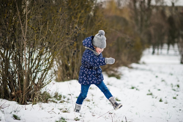 Niña linda divirtiéndose al aire libre en el día de invierno