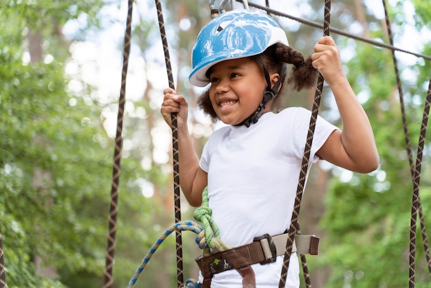 Niña linda divirtiéndose en un parque de aventuras