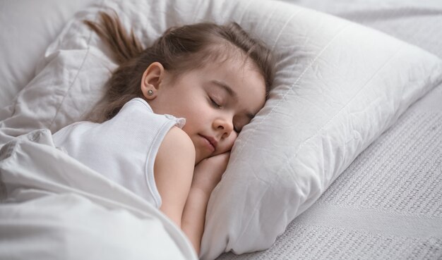 Niña linda duerme dulcemente en la cama