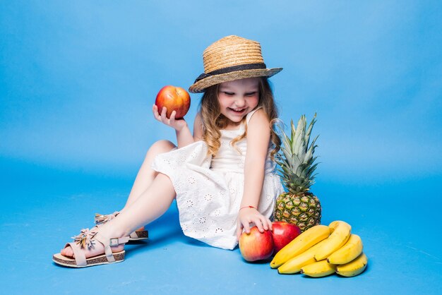 Niña linda con frutas aislado en una pared azul