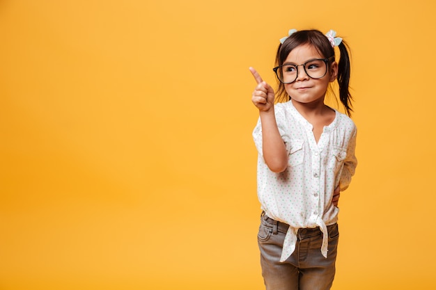 Niña linda con gafas apuntando.