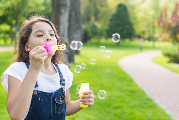 Niña linda haciendo pompas de jabón