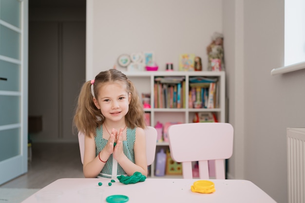 Niña linda moldes de plastilina en la mesa