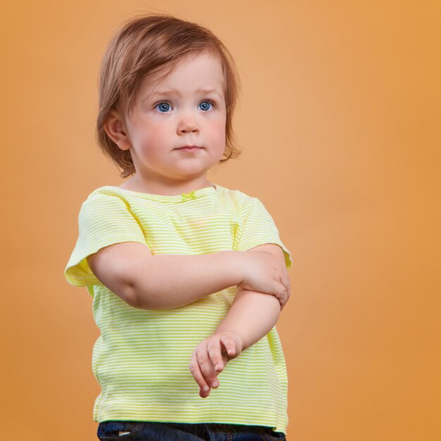 Una niña linda en la pared naranja