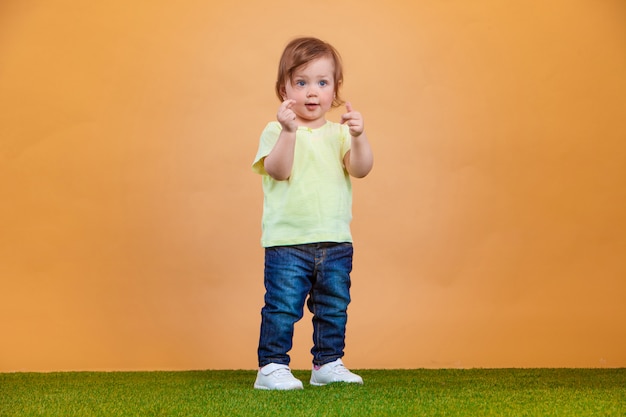 Foto gratuita una niña linda en la pared naranja