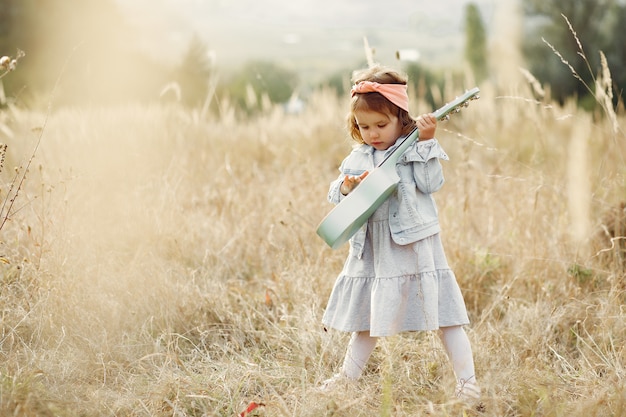 Niña linda en un parque tocando una guitarra