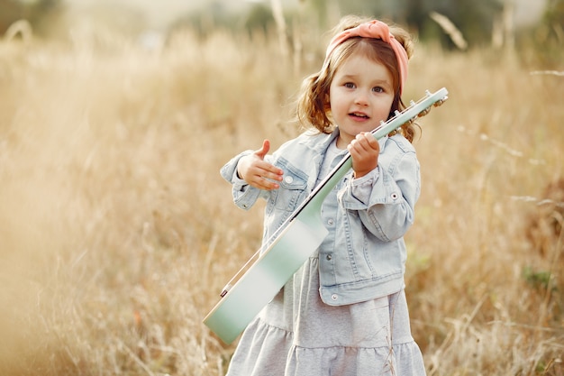 Niña linda en un parque tocando una guitarra