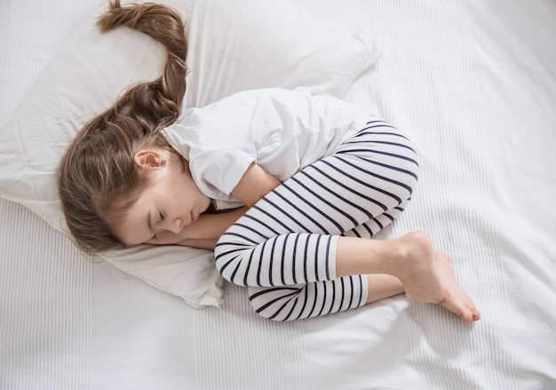 Niña linda con pelo largo durmiendo en la cama