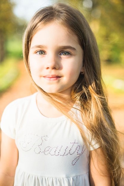 Niña linda con el pelo largo en vestido blanco