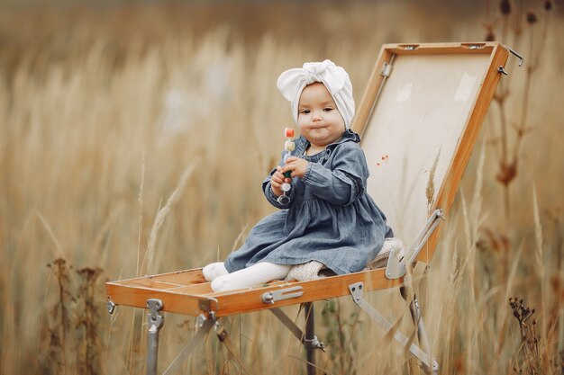 Niña linda pintando en un campo de otoño