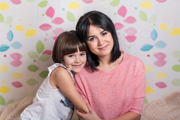 Niña linda que abraza a la madre feliz