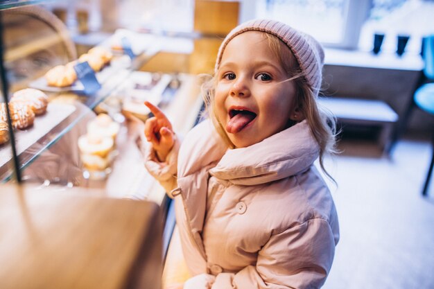 Niña linda que elige el postre en una panadería