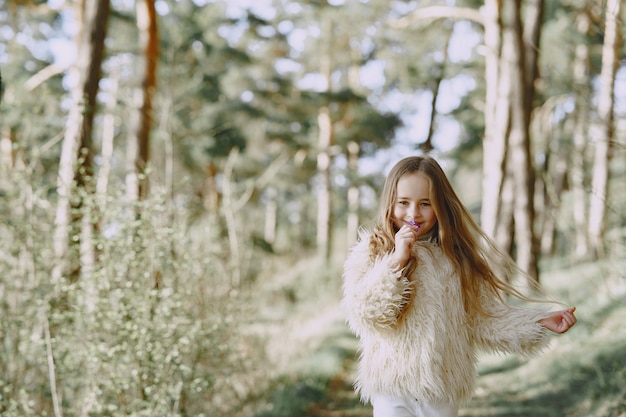 Niña linda que juega en un bosque de verano