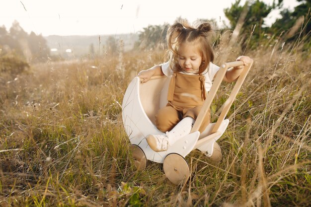 Niña linda que juega en un parque con el carro blanco