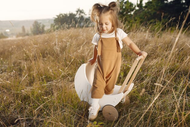 Niña linda que juega en un parque con el carro blanco