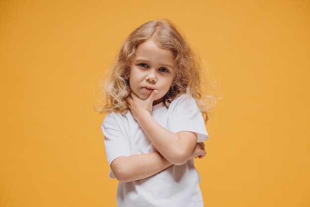 Niña linda que muestra emociones, aisladas sobre fondo amarillo