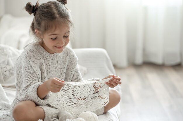 Niña linda que sostiene una servilleta calada hecha a mano en sus manos.