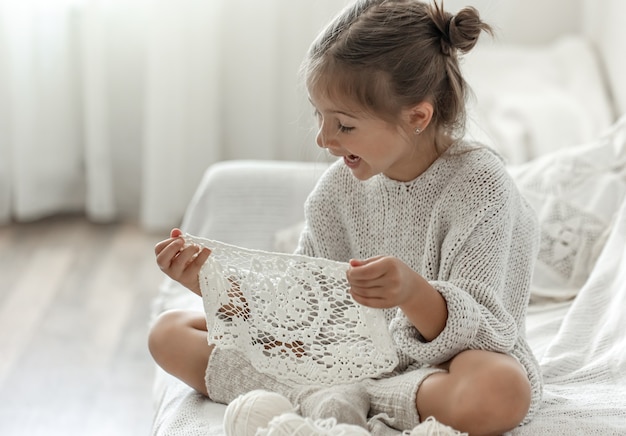 Niña linda que sostiene una servilleta calada hecha a mano en sus manos.