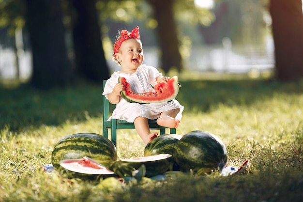 Niña linda con sandías en un parque