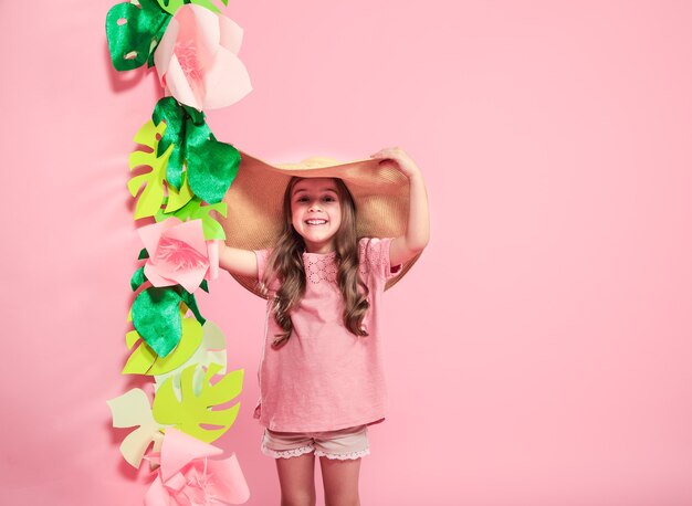 Niña linda con sombrero de verano sobre fondo de color