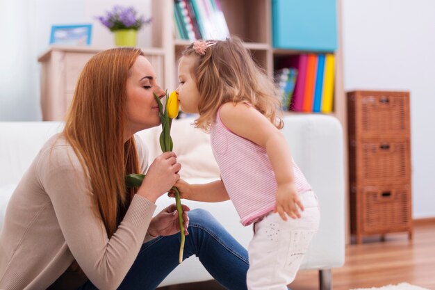 Niña linda con su madre oliendo tulipán fresco