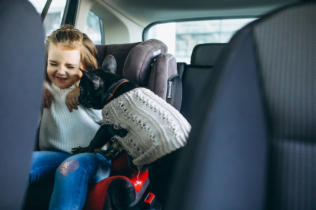 Niña linda con su mascota sentada en la parte trasera de un automóvil