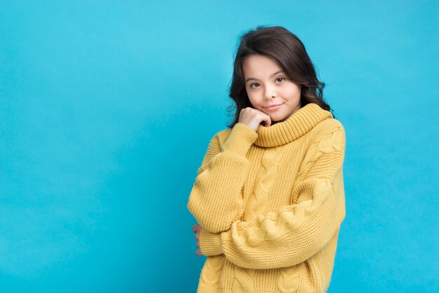 Niña linda en un suéter amarillo sobre fondo azul