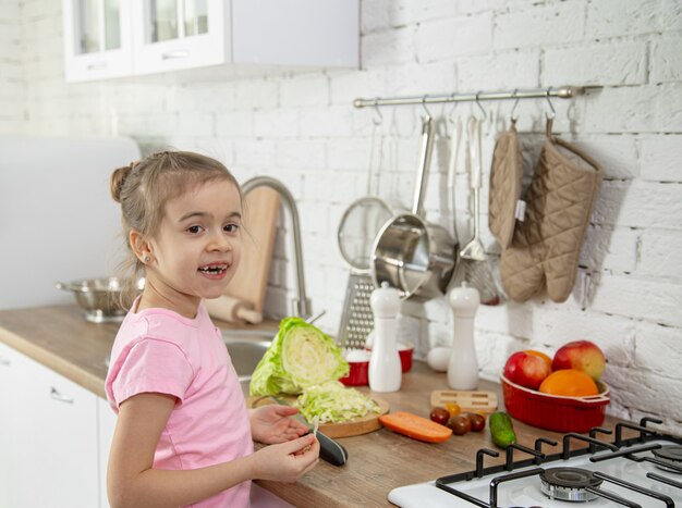 Niña linda con verduras en la cocina. El concepto de una dieta y un estilo de vida saludables. Valor familiar.