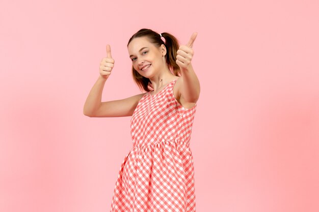 niña en lindo vestido brillante con expresión feliz en rosa