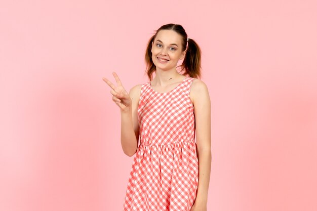 niña en lindo vestido brillante con expresión sonriente en rosa