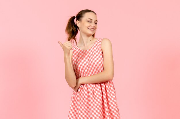 niña en lindo vestido brillante con expresión sonriente en rosa