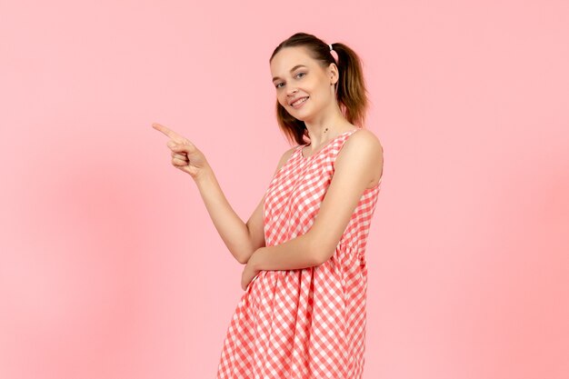 niña en lindo vestido brillante con expresión sonriente en rosa