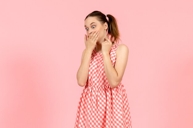 niña en lindo vestido brillante con expresión de sorpresa en rosa