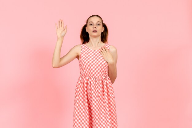 niña con lindo vestido brillante levantando la mano en rosa