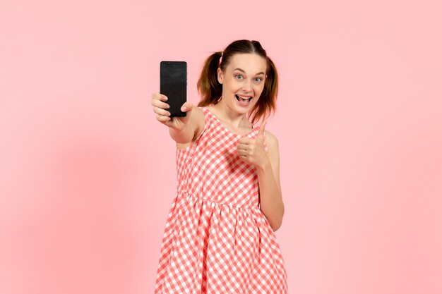 niña en lindo vestido brillante sosteniendo el teléfono en rosa