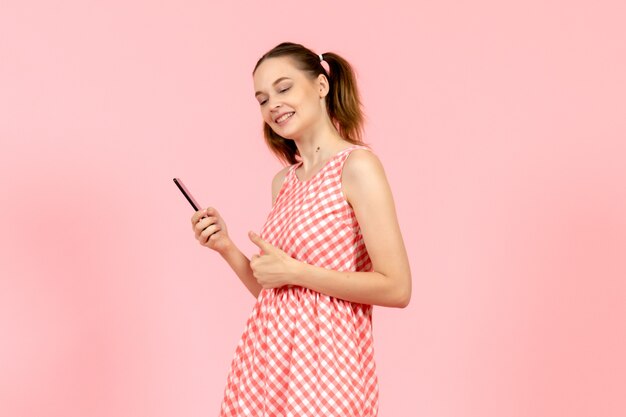 niña en lindo vestido brillante sosteniendo el teléfono en rosa