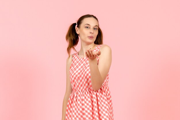 niña en lindo vestido rosa enviando besos al aire en rosa