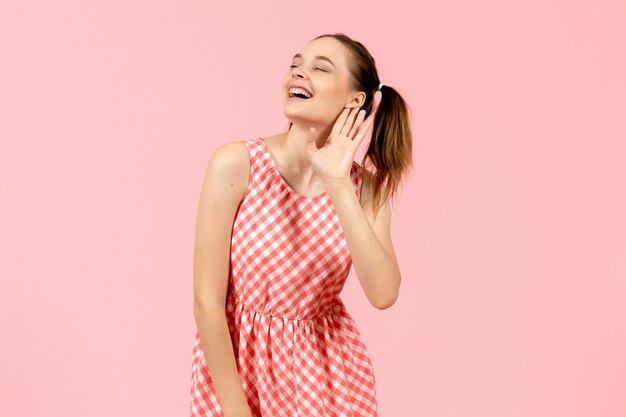 niña en lindo vestido rosa escuchando atentamente y sonriendo en rosa