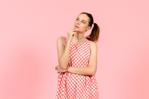 niña en lindo vestido rosa con expresión de pensamiento en rosa