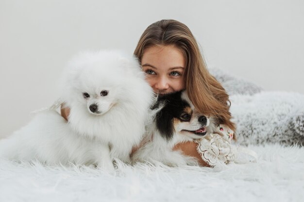 Niña y lindos cachorros blancos sentados en la cama