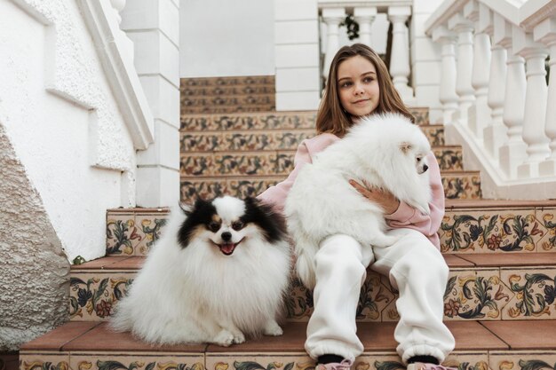 Niña y lindos cachorros blancos sentados en las escaleras