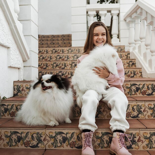 Niña y lindos cachorros blancos sentados en las escaleras