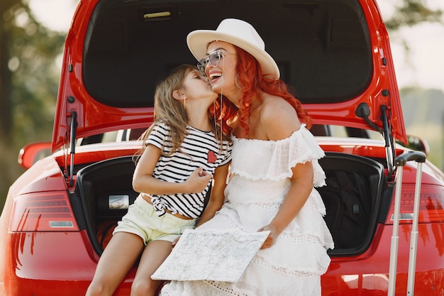 Niña lista para ir de vacaciones. Madre con hija examinando un mapa. Viajar en coche con niños.