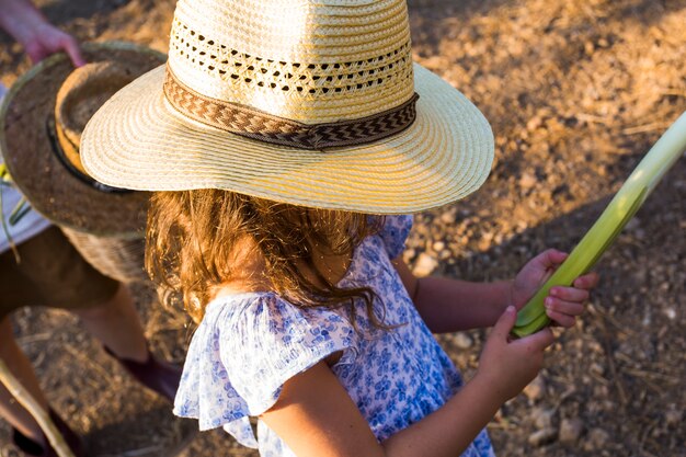 Niña, llevando, sombrero, tenencia, cosechado, puerro, en, manos