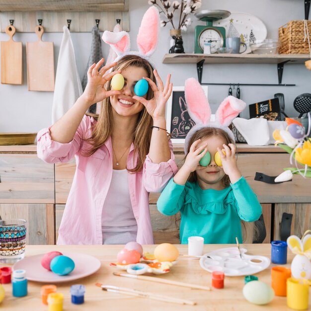 Niña y madre con huevos de Pascua en los ojos