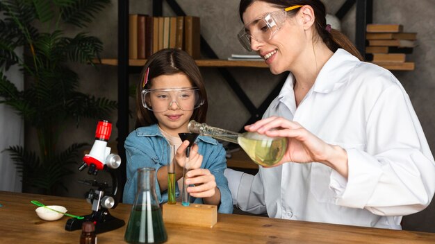 Niña y maestra haciendo experimentos científicos.