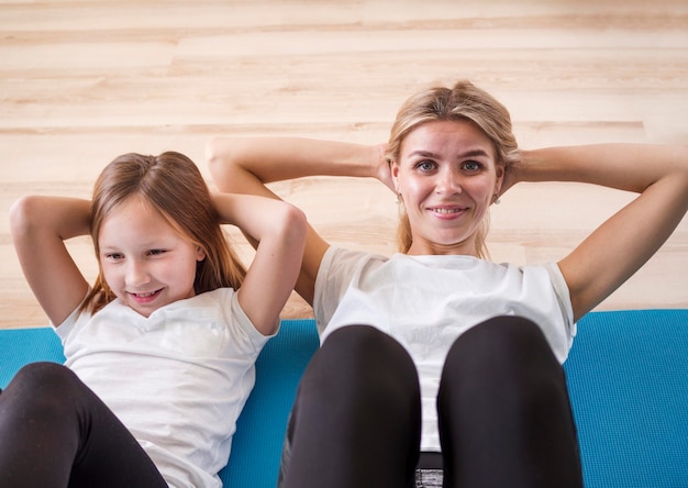 Foto gratuita niña y mamá haciendo ejercicios abdominales