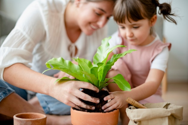 Niña y mamá macetas con plantas en casa