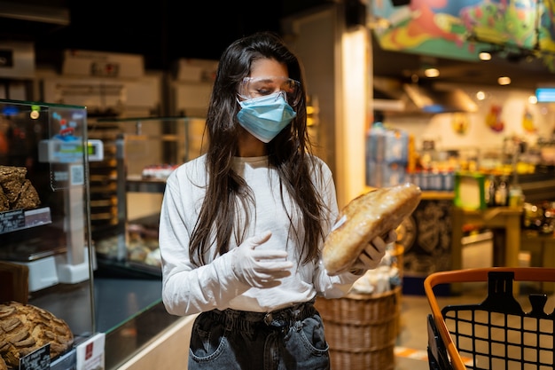 Foto gratuita la niña con mascarilla quirúrgica va a comprar pan.